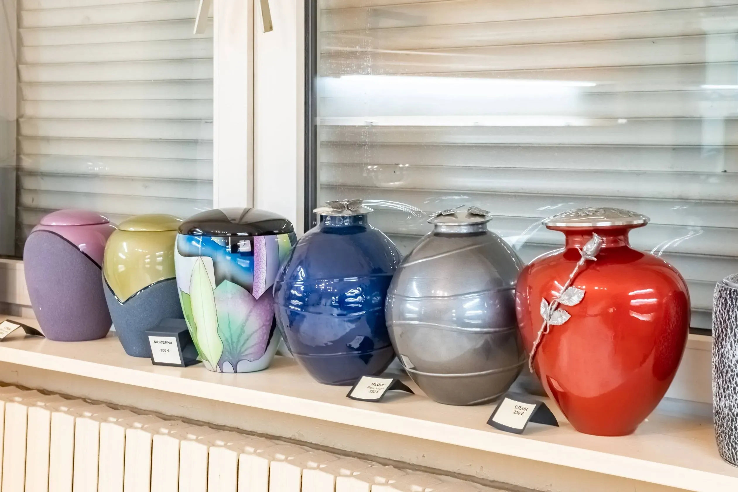 Collection d'urnes funéraires colorées exposées dans un magasin.