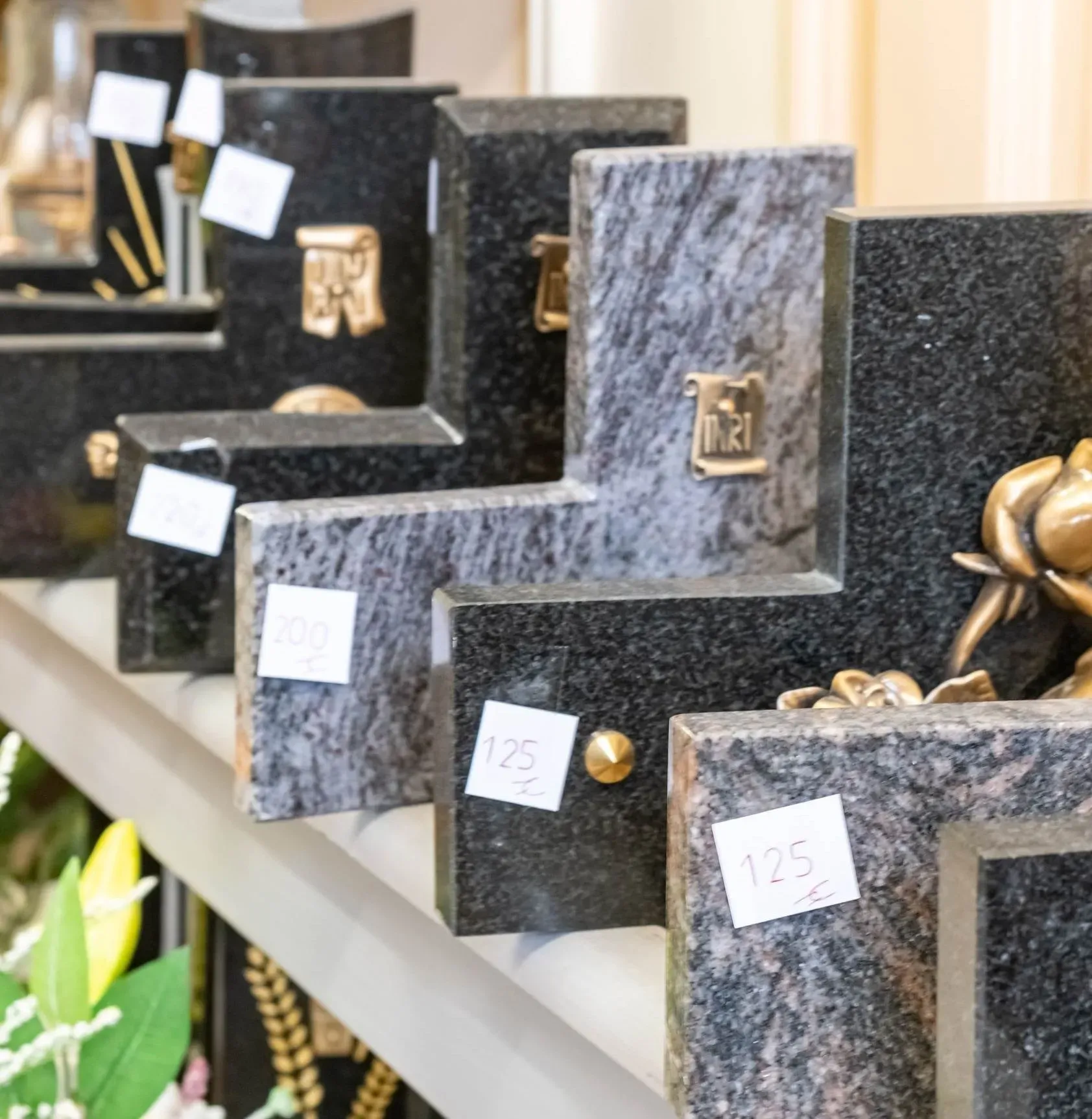 Plaques funéraires en granit de différentes formes exposées avec prix.