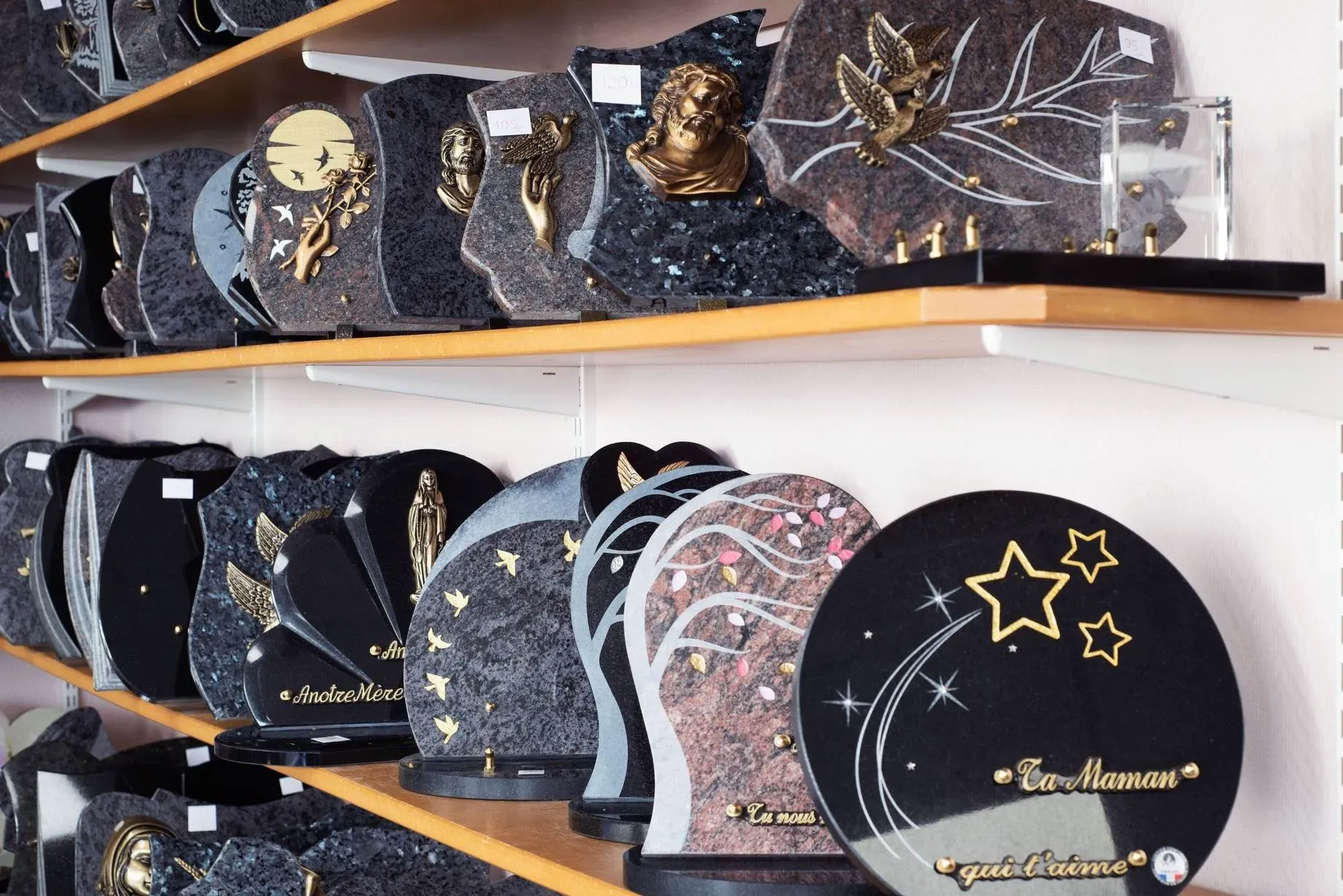 Plaques funéraires personnalisées en granit sur étagères de présentation.