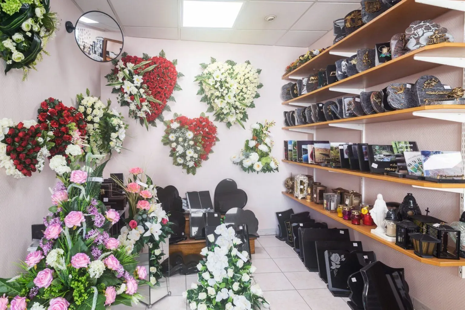 Intérieur d'un magasin funéraire avec fleurs artificielles en cœur et plaques de marbre.