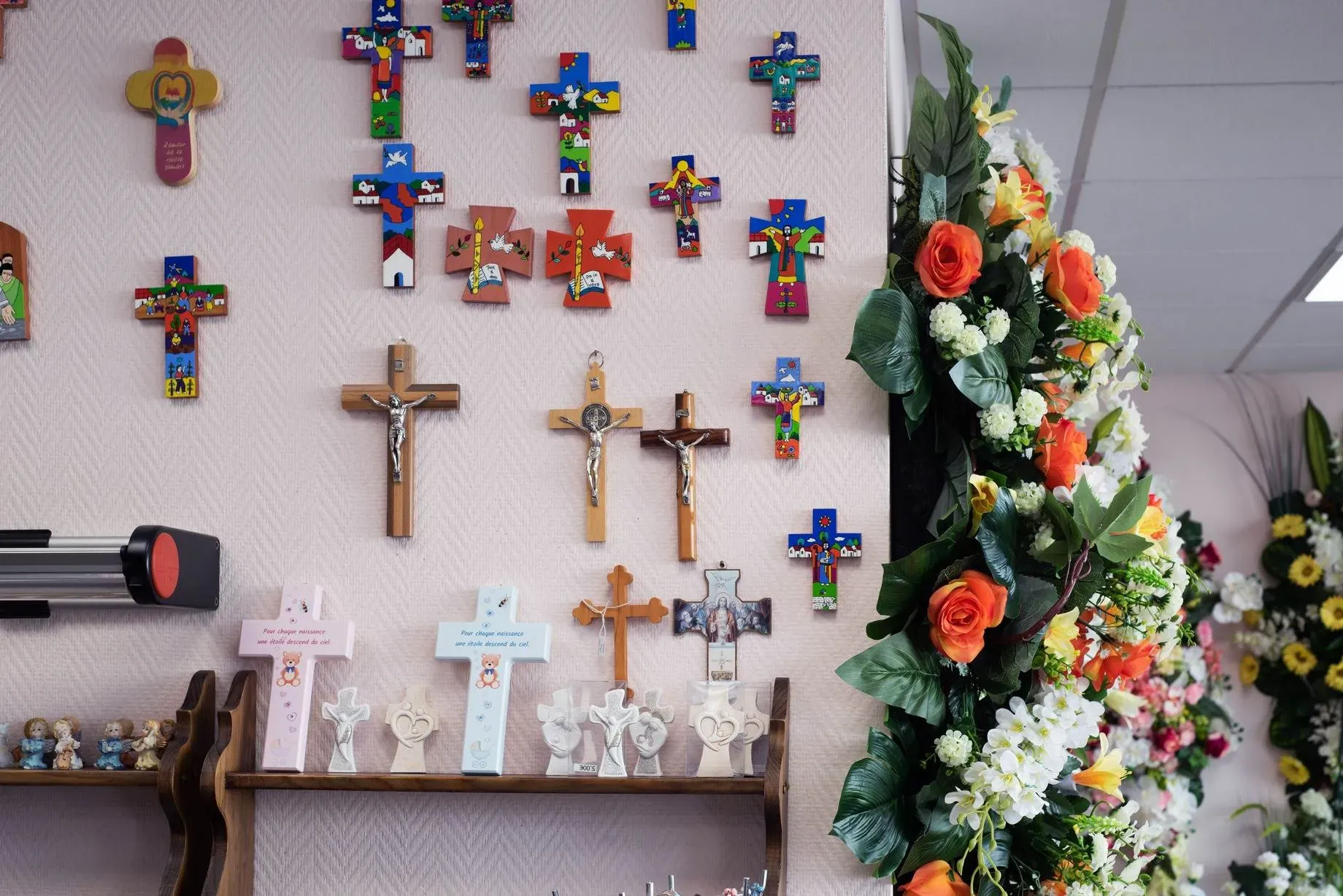Mur décoré de croix chrétiennes et arrangements floraux funéraires.