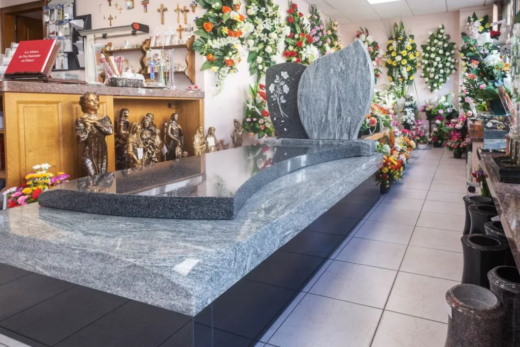 Exposition de monuments funéraires en granit et compositions florales en magasin.