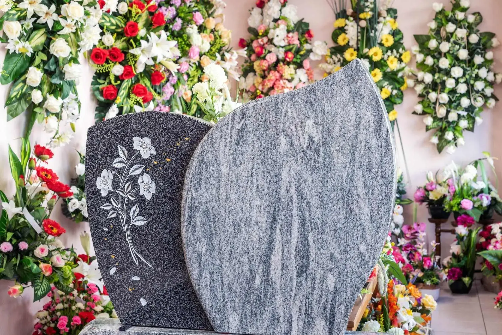 Stèle funéraire bicolore gravée avec fleurs blanches en premier plan.