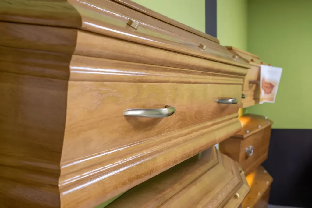 Gros plan sur la finition en bois verni et poignées d'un cercueil funéraire.