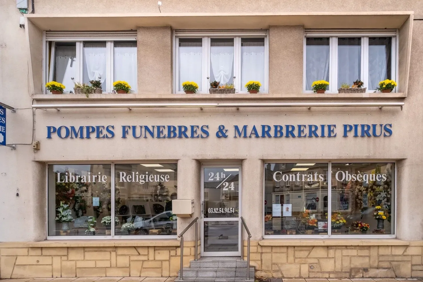 Façade de l'agence Pompes Funèbres et Marbrerie Pirus avec vitrines.