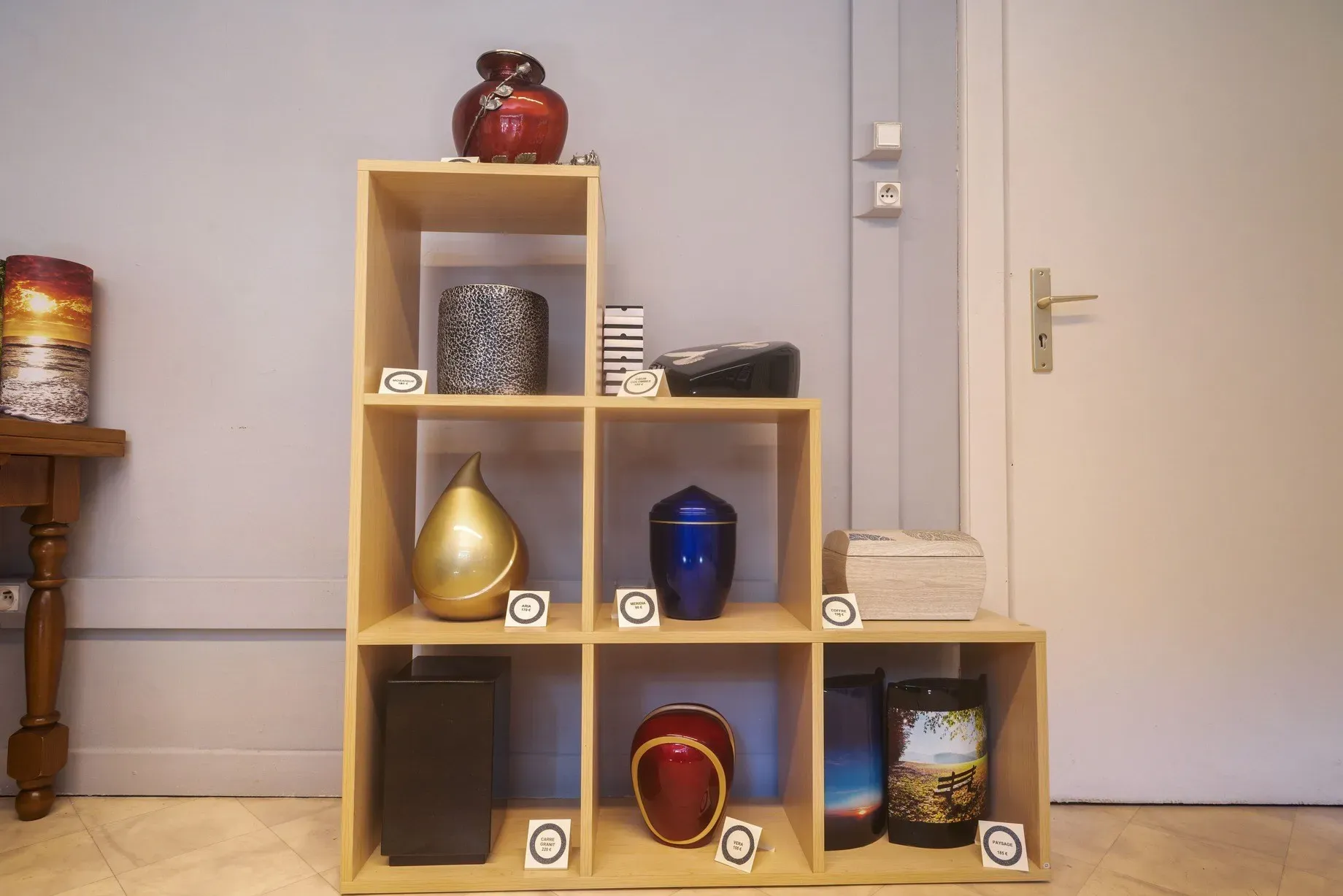 Urne funéraire et statuettes d'anges sur un comptoir de marbrerie.