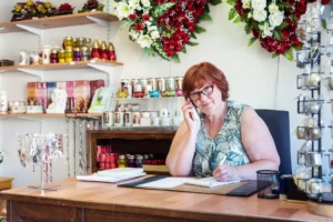 Conseillère PIRUS au téléphone, articles religieux et fleurs en boutique.