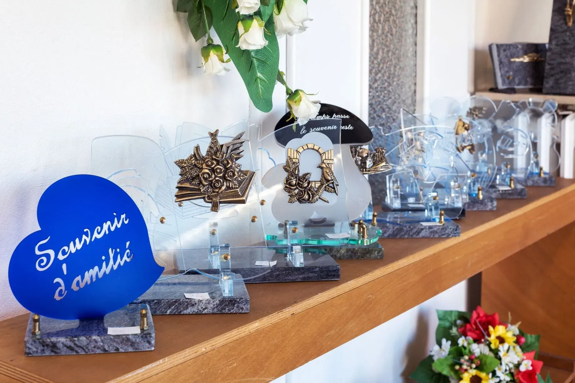 Plaques funéraires en verre avec motifs et socle en granit sur étagère.